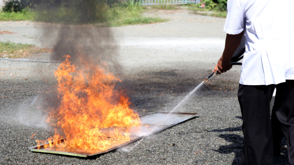 A man extinguishing a fire with a hose.